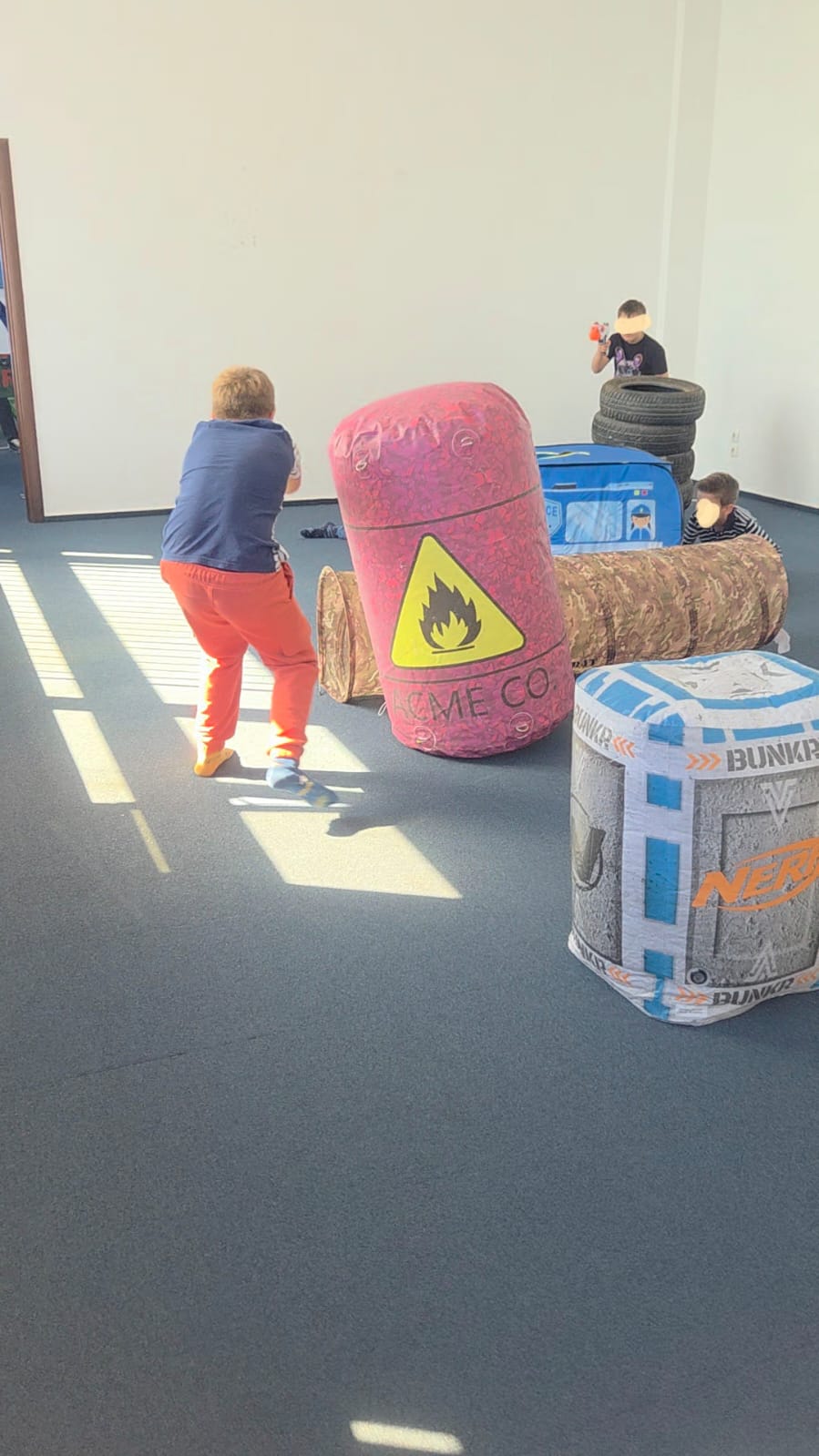 Copii jucand NERF party in interior cu blastere, ochelari de protectie și gloante
