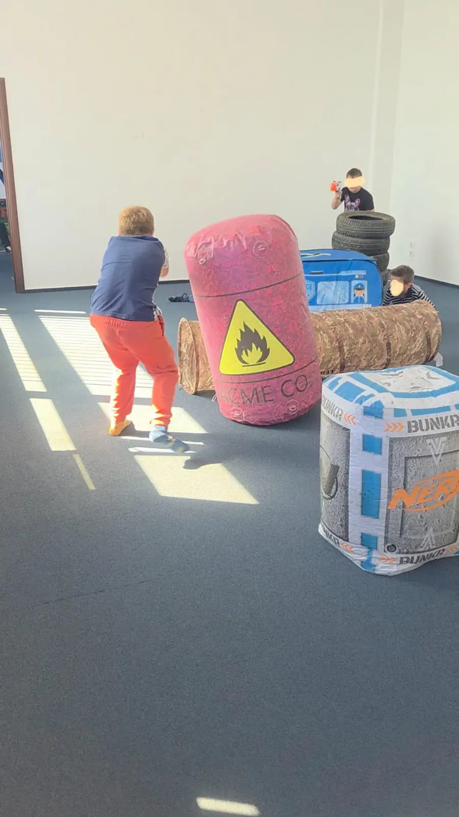 Copii jucand NERF party in interior cu blastere, ochelari de protectie și gloante